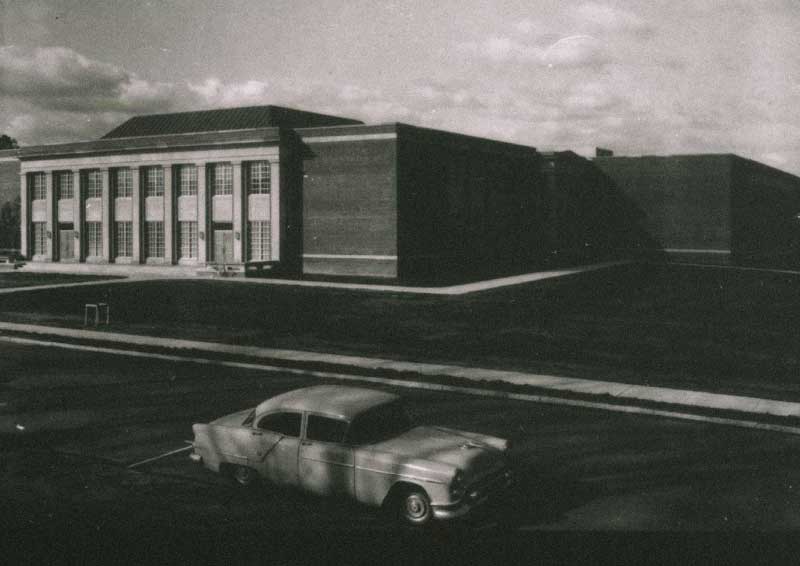 Black and white photo of law school building in 1960s with antique car in front